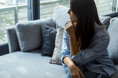 Young woman using phone while sitting on sofa at home