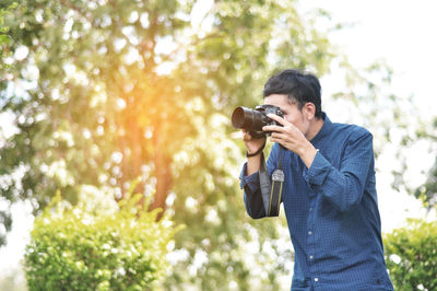 Young woman photographing against trees