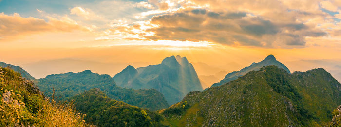 Panoramic beautiful scenic mountain range with blue sky, cloud and blast horizon sun with tourists