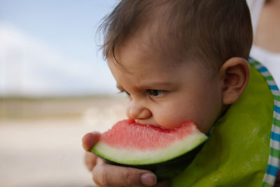 Close-up of cute baby girl eating watermelon outdoors