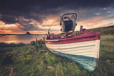 Boat moored at sea shore against sky during sunset