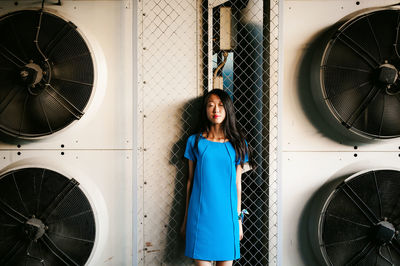 Young woman standing amidst exhaust fans