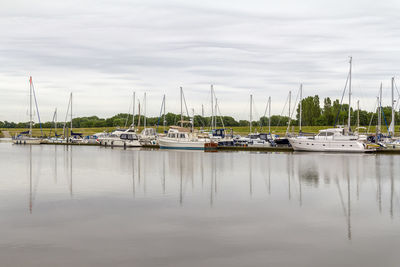 Sailboats moored in lake against sky