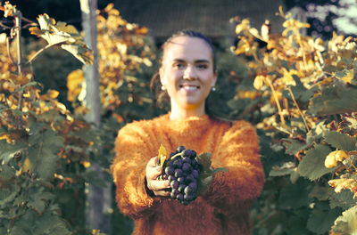 Portrait of young woman holding grapes