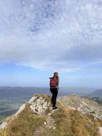 Rear view of woman standing on rock against sky