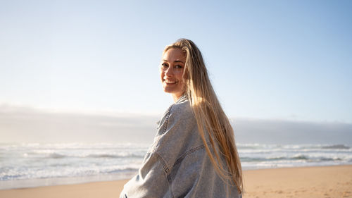 Rear view of woman standing at beach against clear sky