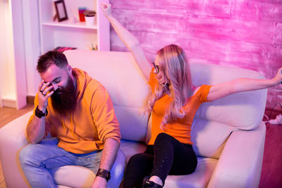 Side view of young woman sitting on sofa at home