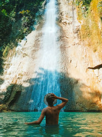 Rear view of shirtless man in watter fall