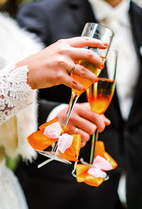 Cropped image of newlywed couple holding champagne in wedding ceremony