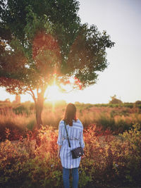 Rear view of woman standing on field against sky