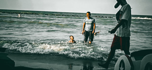 People standing on beach against sky