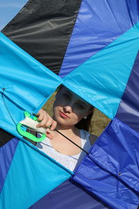 Portrait of woman seen through blue kite during sunny day