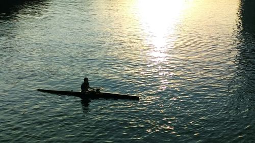 Man in boat on sea against sky during sunset