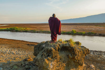 Rear view of a man wearing masai clothes standing on a scenic view point at lake natron, tanzania