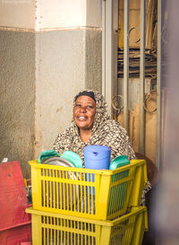 Portrait of smiling young woman standing by wall, she also making tea for people in street  