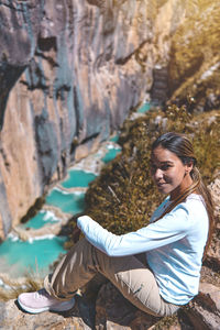Side view of woman sitting on rock
