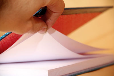 Close-up of hand holding book on table