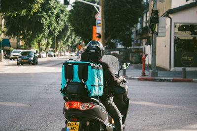 Rear view of people riding motorcycle on road