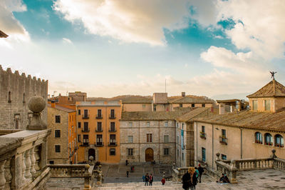 People on street by buildings in town against sky