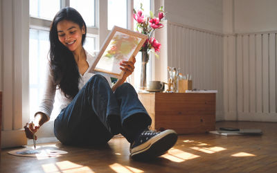 Portrait of young woman sitting on table at home