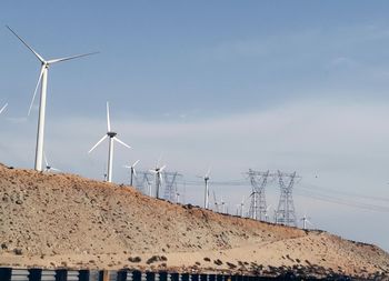 Windmills on landscape against sky