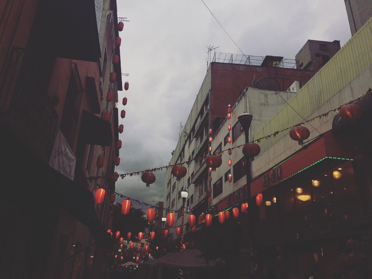 built structure, architecture, building exterior, city, residential building, residential structure, low angle view, street, building, sky, city life, cloud, dark, narrow, no people, residential district, laundry, cloud - sky