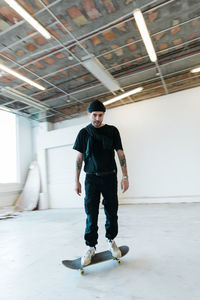 Portrait of young man standing on skateboard