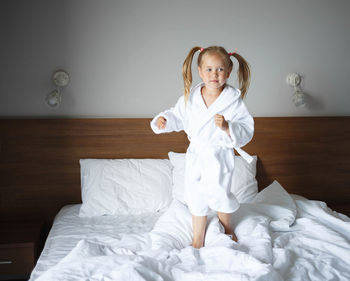 Full length of girl standing on bed at home