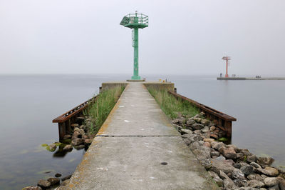 Walkway by sea against sky