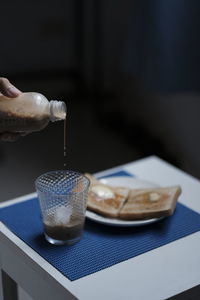 Close-up of hand holding drink on table