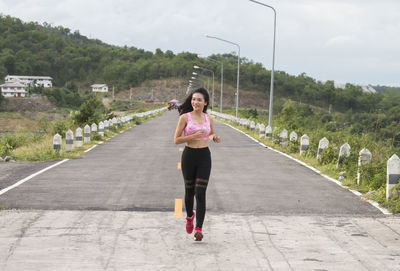 Full length of woman standing on road against trees