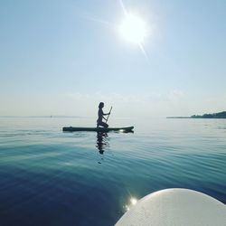 Woman paddleboarding in sea against sky