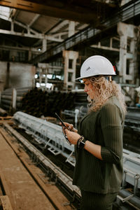 Woman holding mobile phone while standing at home