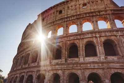 Low angle view of coliseum against bright sky