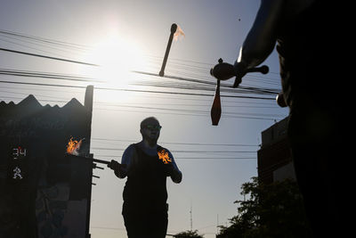 Silhouette men standing on street against sky during sunset