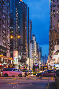 Cars on city street by buildings against sky