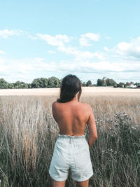 Rear view of man standing on field against sky