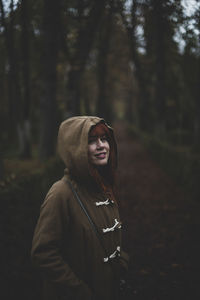 Portrait of young woman standing against trees