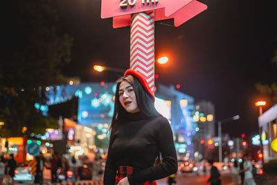 Woman standing on illuminated street at night