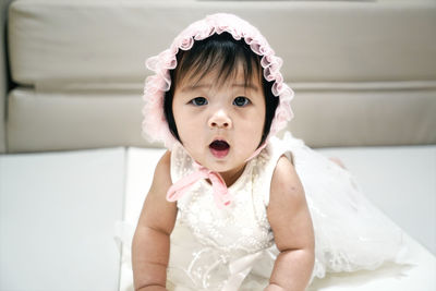 Portrait of cute girl open mouth wear white hat is crawling on the cushion and looking at camera. 