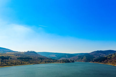 View from the air onto a dam with an asphalted country road at the edge