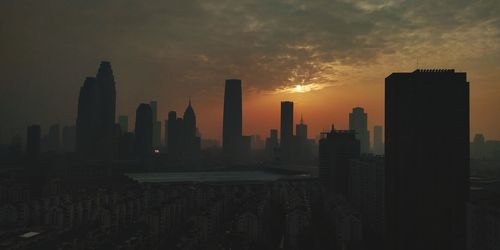 Silhouette of buildings in city during sunset