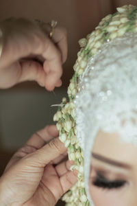 Cropped hands adjusting flowers in bride head