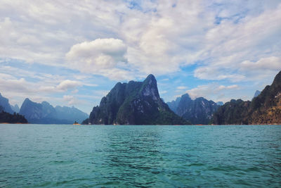 Scenic view of sea by mountains against sky