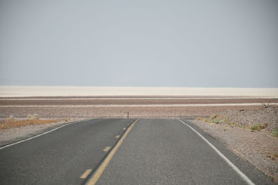 Road passing through land against clear sky