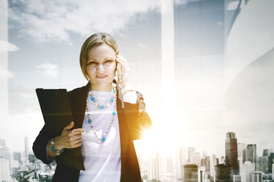 Young woman looking at cityscape against sky