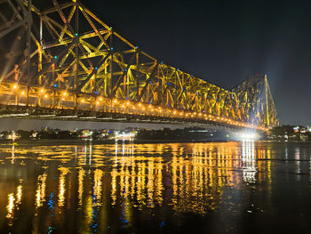 Illuminated bridge over river at night