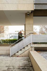 Bearded man with coat walking up stairs and looking away