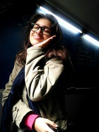 Low angle view of smiling young woman wearing eyeglasses