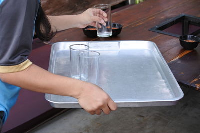 Midsection of waitress picking empty drinking glasses